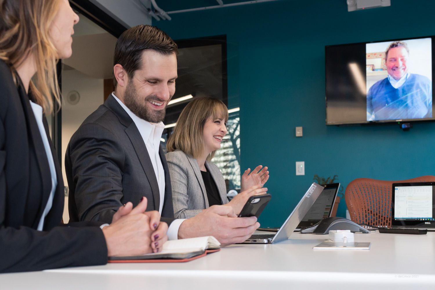 People in a business meeting, two smiling, with laptops and video call screen in view. DEC_2669.jpg