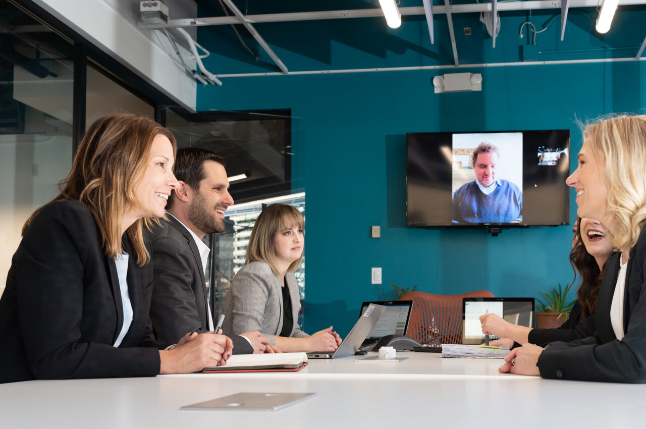 People in a conference room engaged in a video call meeting, smiling and attentive