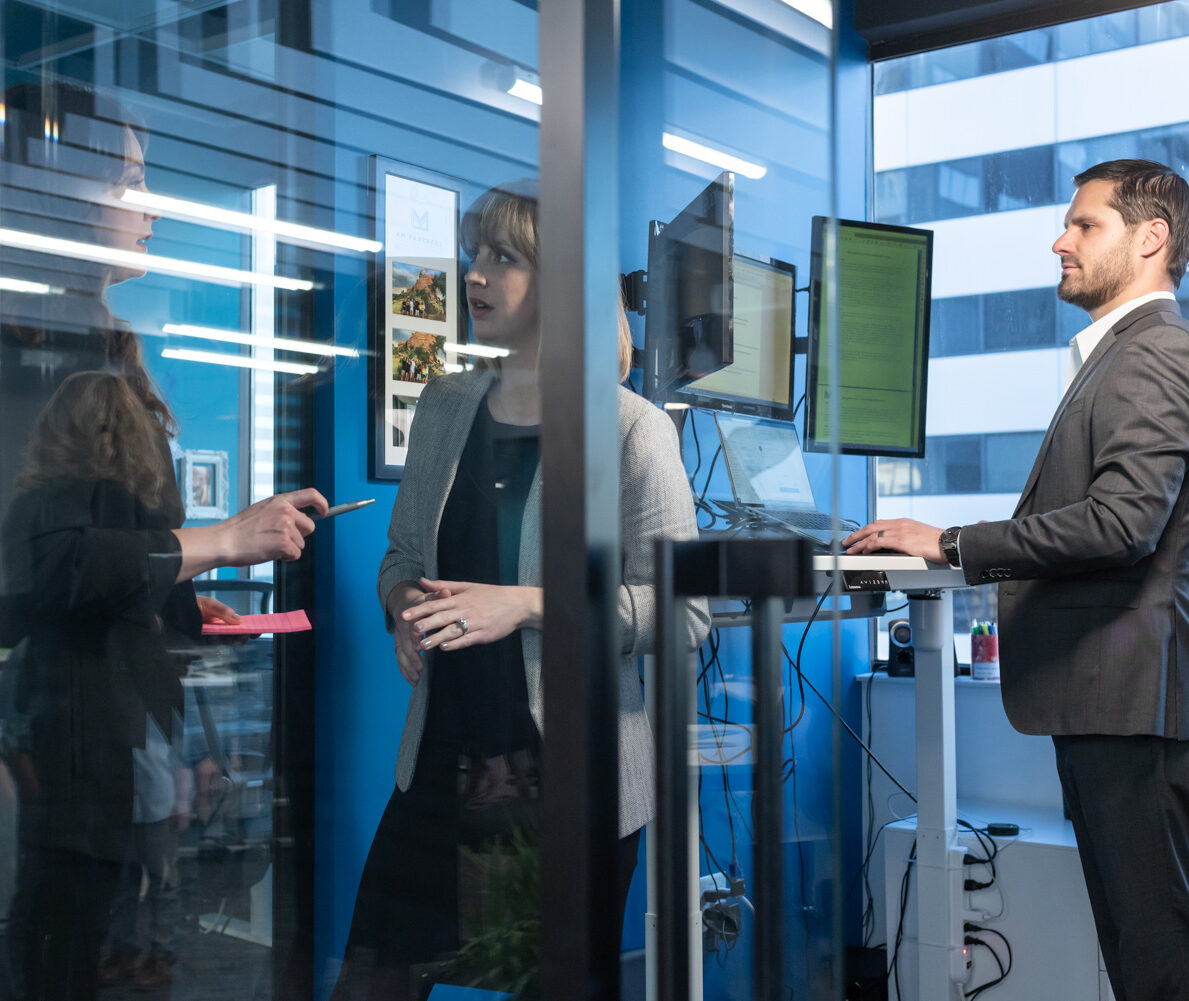 Three people in an office; one standing, two conversing through glass. DEC_2744.jpg