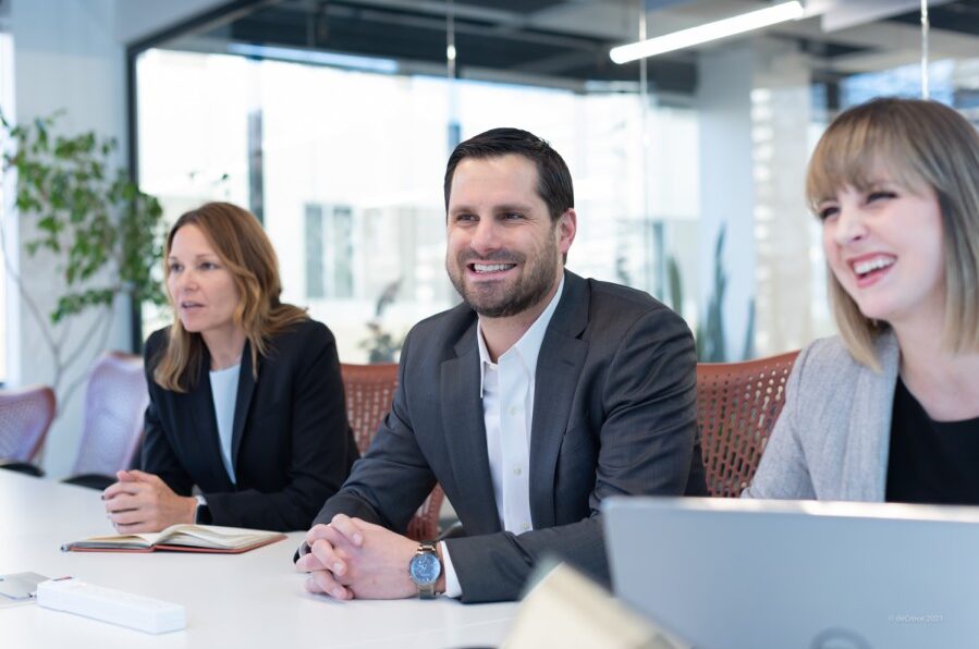 Three people in a meeting room, smiling and engaged