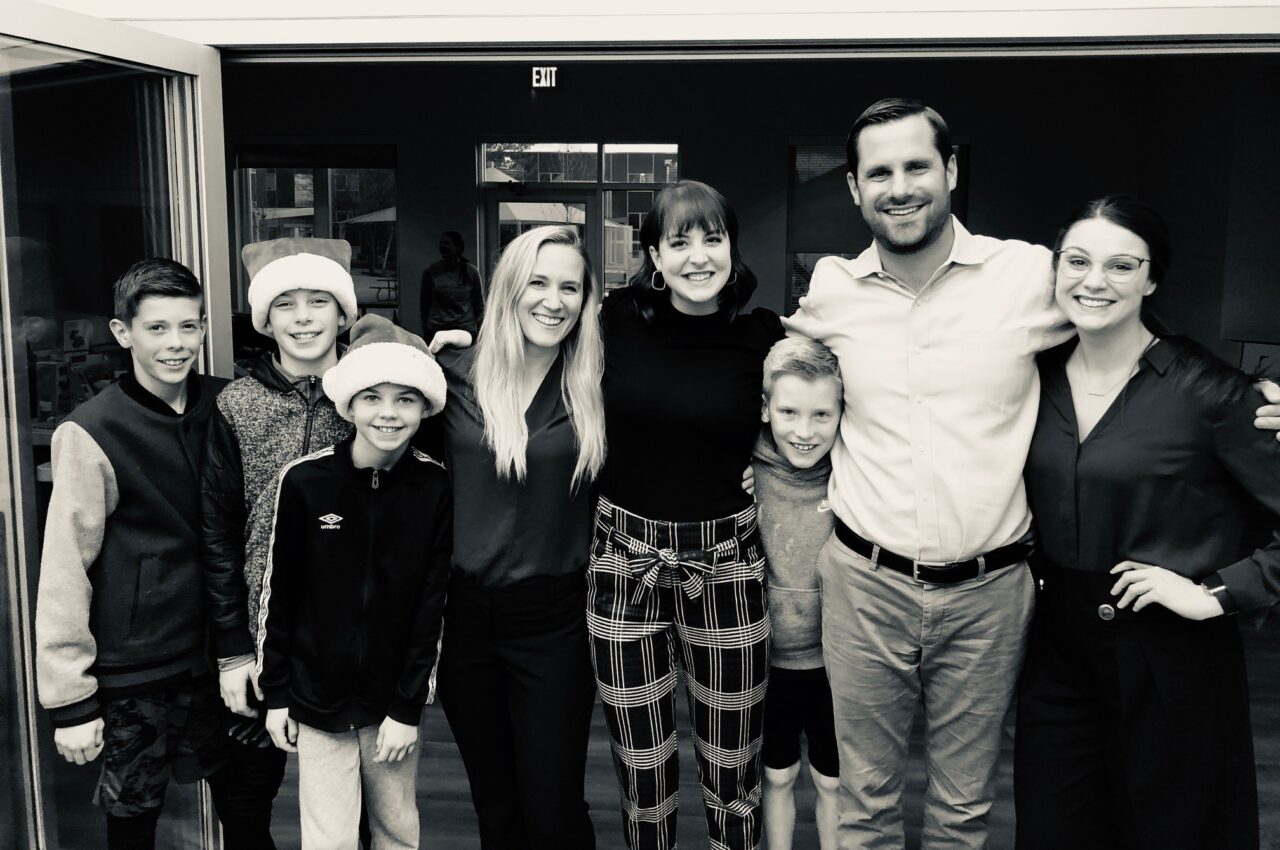 Group smiling indoors, children in Santa hats, casual happy moment