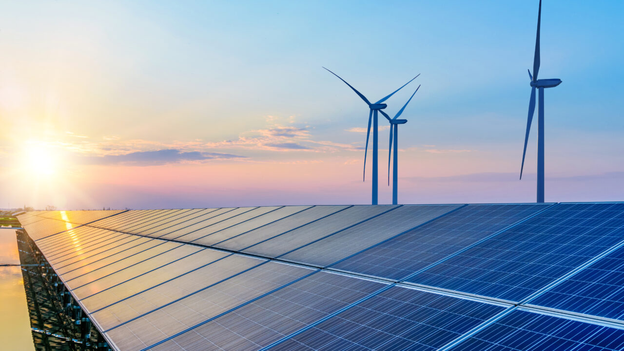 Solar panels and wind turbines at sunrise, symbolizing renewable energy